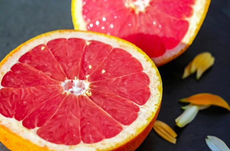 Top Best Fruits for Weight Loss 1 | eat move healthy Close-up of juicy grapefruit halves showcasing vibrant red pulp on a dark background.
