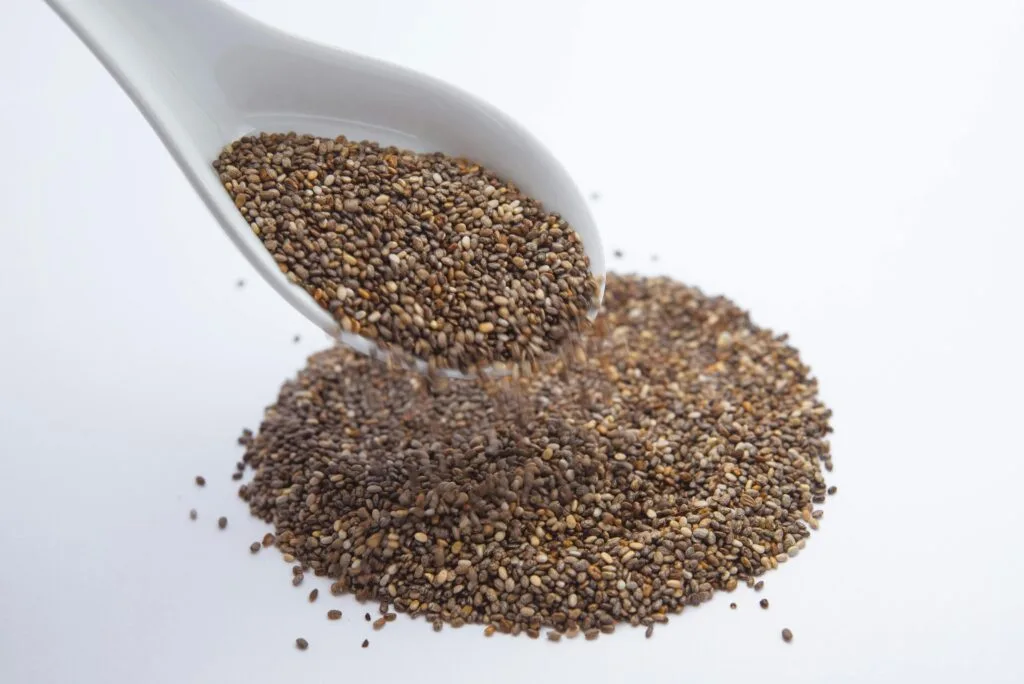 Delicious Easter Recipes with Egg Substitutes 2 | eat move healthy chia seeds pouring from a white ceramic spoon onto a white surface.