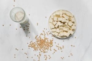 Healthy Grocery List: 50+ Affordable Foods 3 | eat move healthy Top view of tofu cubes, soybeans, and soy milk on a white background β perfect for vegan food themes.