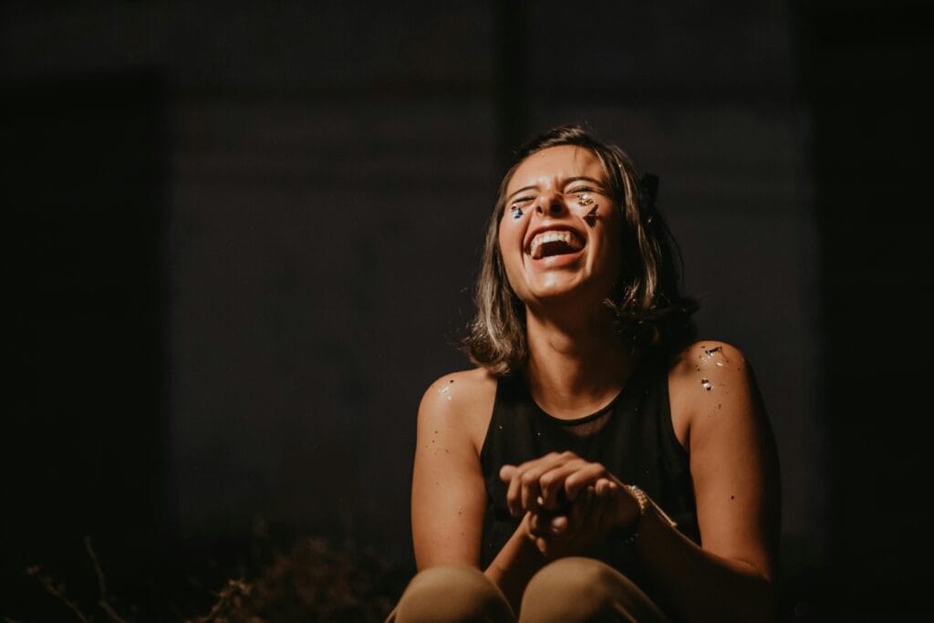 10 Surprising Health Facts You’ve Never Heard 9 | eat move healthy A joyful young woman laughing with confetti on a dark background.