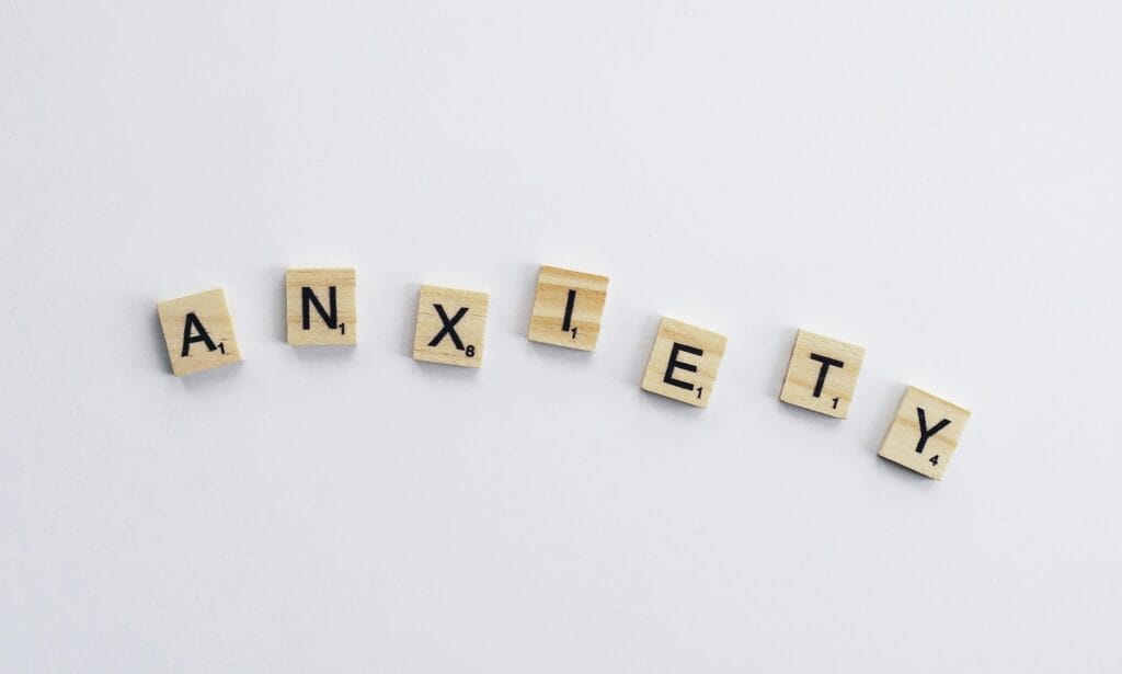 Top 10 Supplements to Lower Cortisol Naturally 4 | eat move healthy Wooden tiles on a white background spell anxiety, symbolizing mental health awareness.