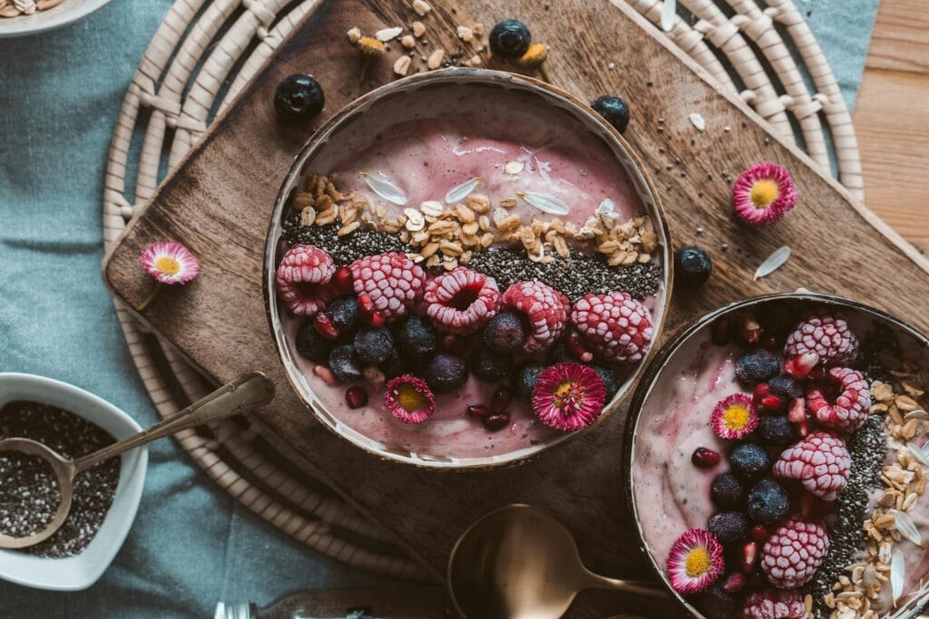 Why You Shouldn't Skip Breakfast Anymore 1 | eat move healthy Delicious smoothie bowls topped with fresh berries, chia seeds, and granola on a rustic wooden table.