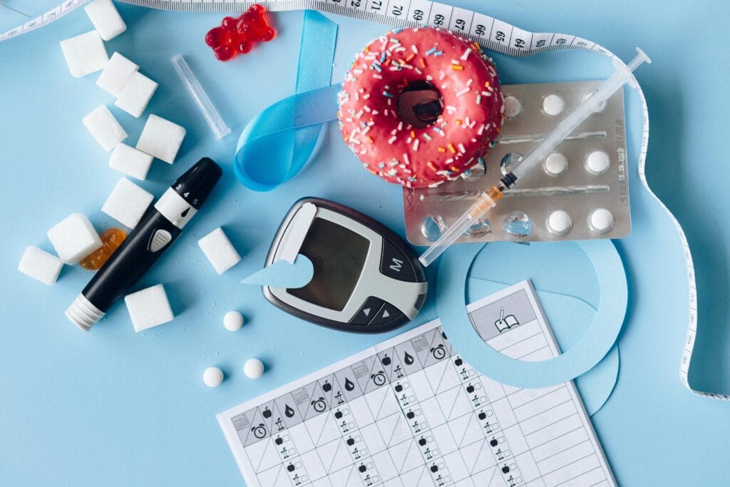 Top 10 Supplements to Lower Cortisol Naturally 5 | eat move healthy Still life image of diabetes management equipment, sweets, and medication arranged artfully on a blue background.