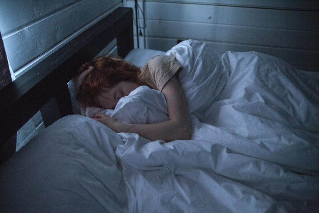 Why You Shouldn't Skip Breakfast Anymore 2 | eat move healthy A woman sleeping peacefully in a cozy bedroom, enveloped by soft white sheets, under the gentle glow of night lighting.