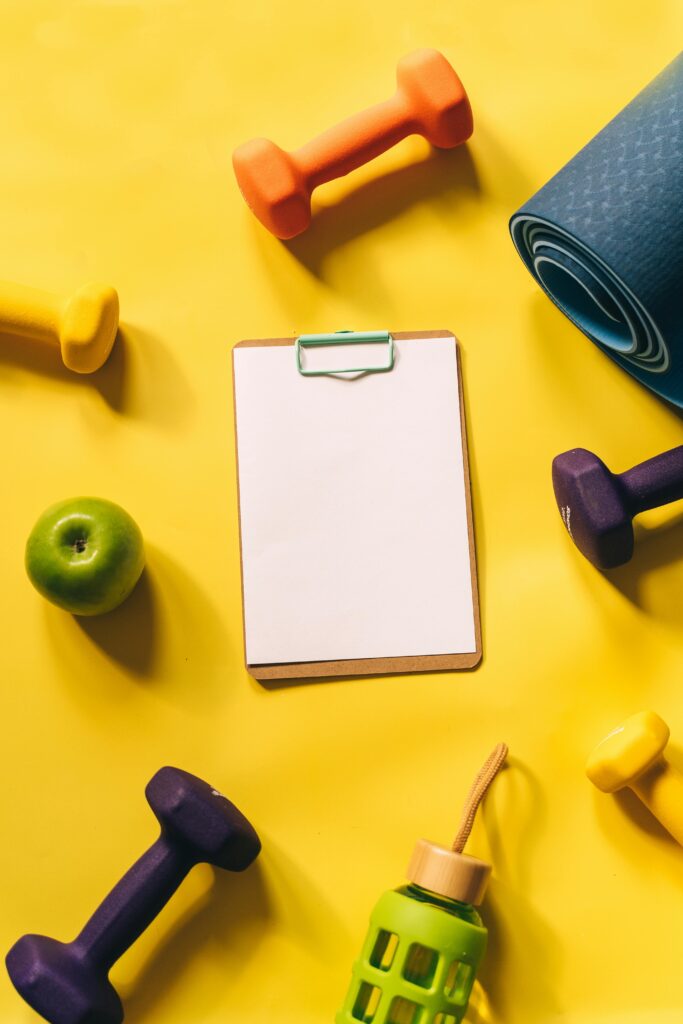How to Stay Motivated with Exercise 3 | eat move healthy Top view of colorful fitness gear and clipboard on yellow background.