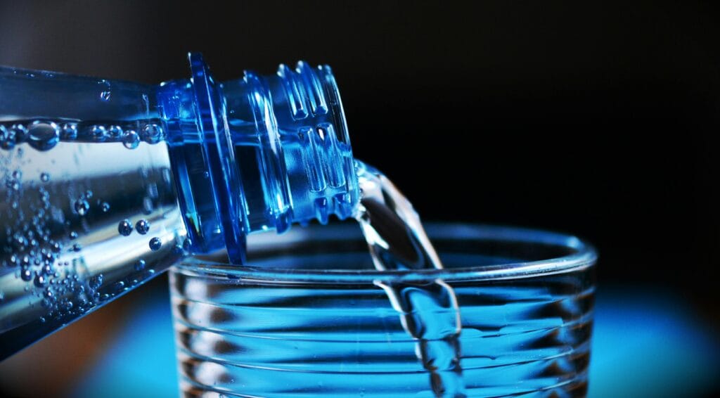 How to Lose Weight With These 10 Tips 2 | eat move healthy Close-up of sparkling water being poured from a bottle into a glass with bubbles visible.