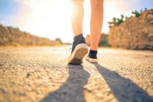 7-Day Reset Plan 4 | eat move healthy A woman walks down a sunlit path in summer, highlighting leisure and travel outdoors.