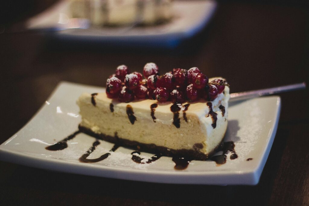 The 80/20 Diet for Weight Loss 3 | eat move healthy Slice of cheesecake topped with berries and chocolate drizzle on a plate.