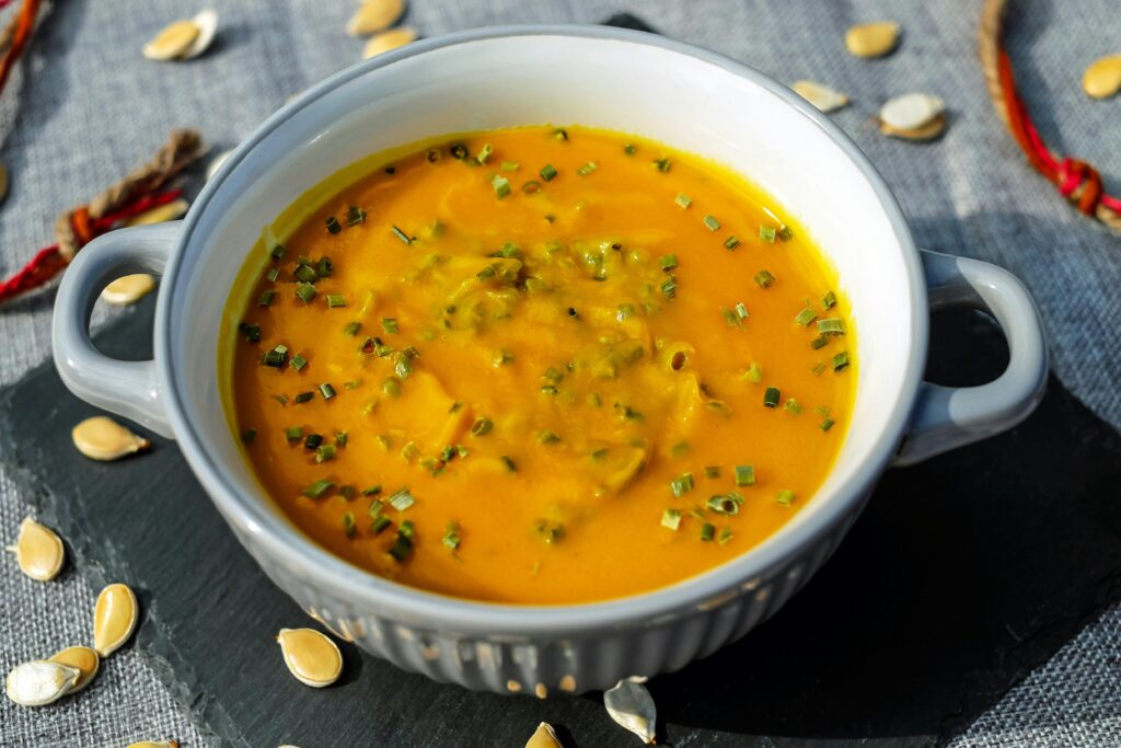 Warm and creamy pumpkin soup garnished with fresh herbs, perfect for a cozy meal.