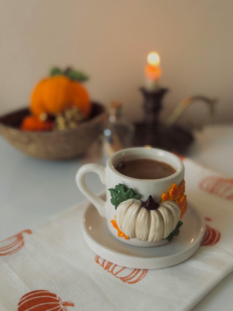 Sugar-Free Pumpkin Cheesecake Bars 3 | eat move healthy Warm coffee in a decorated pumpkin mug, evoking a cozy autumn atmosphere.
