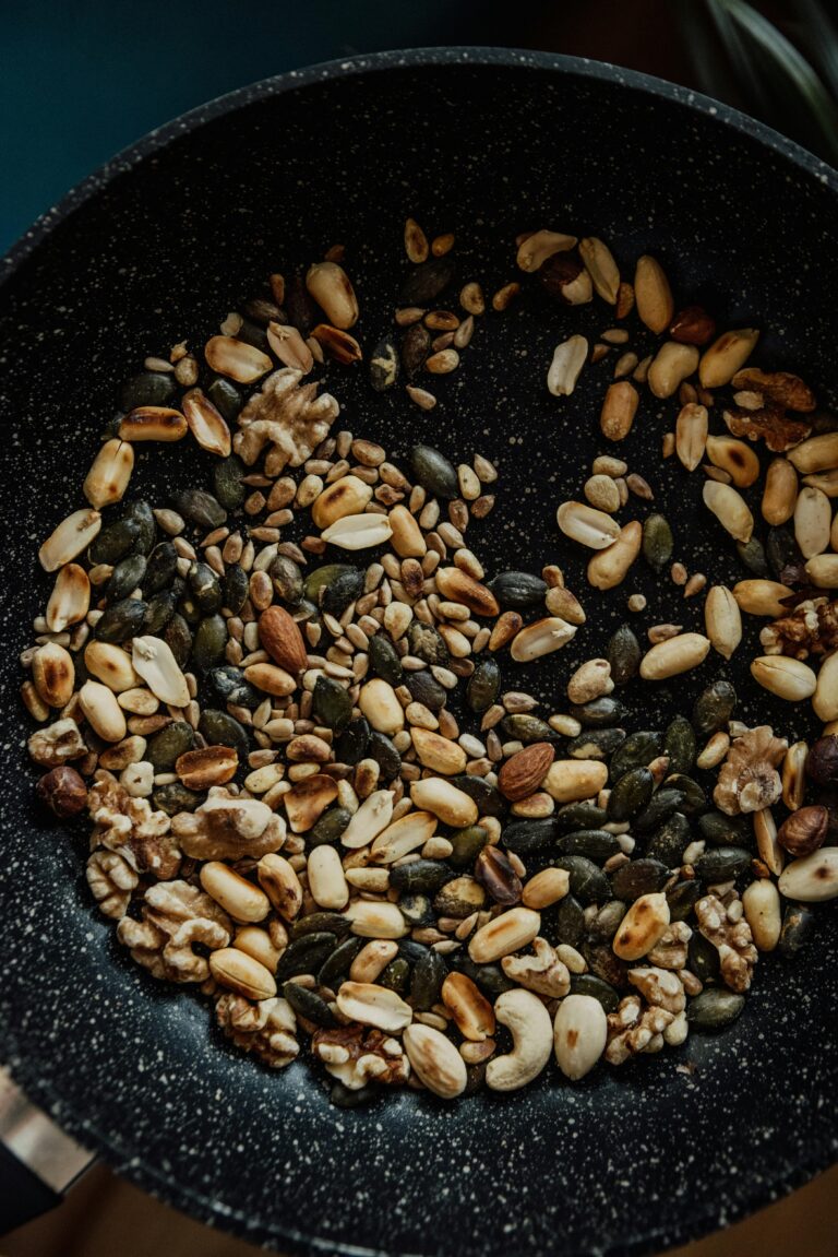 5 Steps Efficient Healthy Meal Planning 6 | eat move healthy Close-up of assorted nuts and seeds roasting in a frying pan, ideal for vegan cooking.