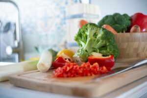Colorful vegetables including broccoli and bell peppers on a chopping board, perfect for healthy cooking concepts.
