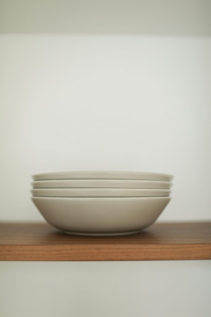 Roasted Veggie & Quinoa Glow Bowl 2 | eat move healthy Minimalist stack of white bowls neatly arranged on a wooden shelf, highlighting kitchenware elegance.