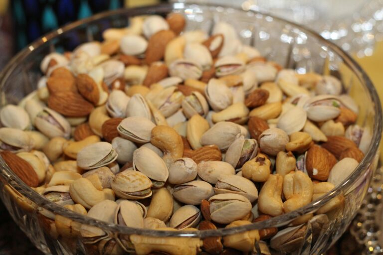 The Best Plant-Based Proteins 13 | eat move healthy A close-up view of a glass bowl filled with various mixed nuts, including almonds, cashews, and pistachios.