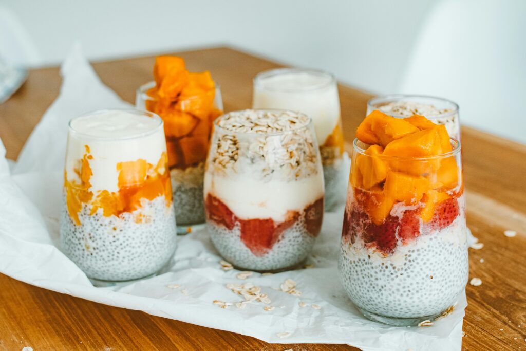 Creamy Vanilla Chia Pudding 3 | eat move healthy Delicious chia pudding parfaits with mango and strawberry layers on a wooden table.