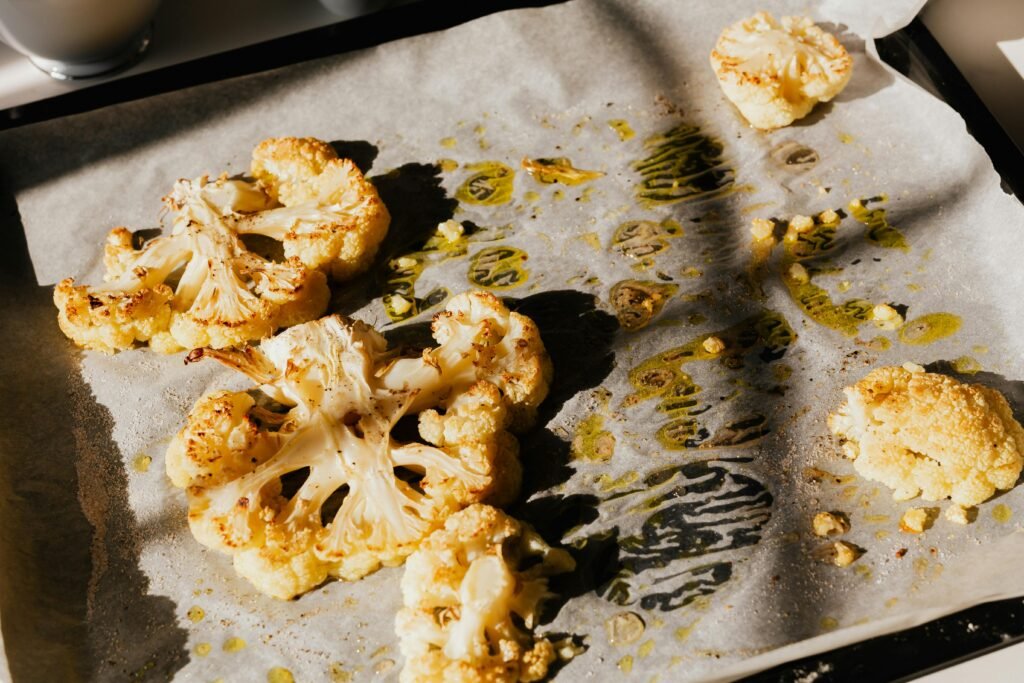 Low-Carb Sugar-Free Sesame Cauliflower 1 | eat move healthy Golden roasted cauliflower slices on baking paper, seasoned with herbs and olive oil.